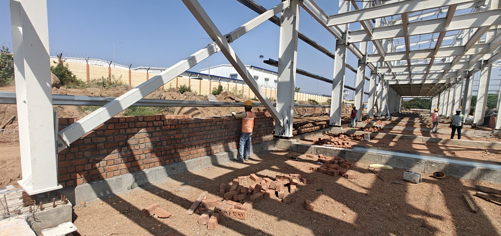 Workers building a brick infill wall between steel columns at the UUV Missile Complex
